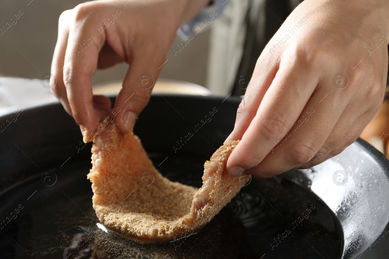 Photo of Cooking schnitzel. Woman putting raw pork chop in bread crumbs into frying pan, closeup