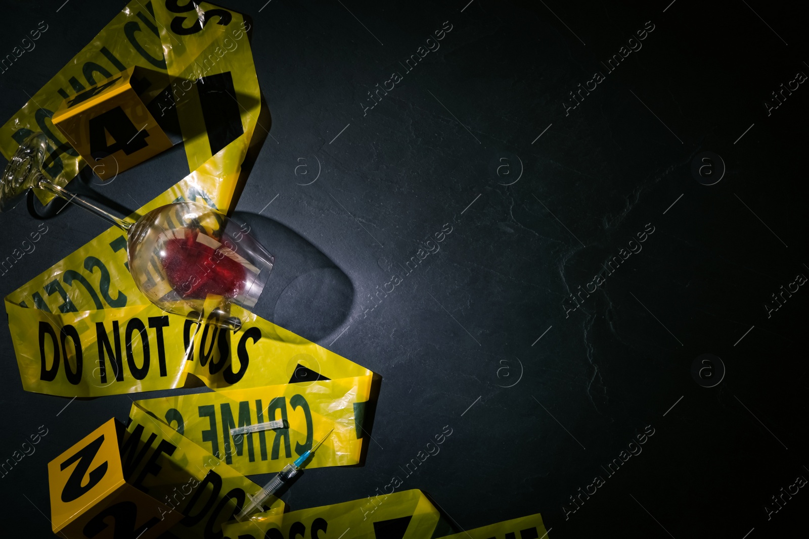 Photo of Flat lay composition with evidences and crime scene tape on black slate background, space for text