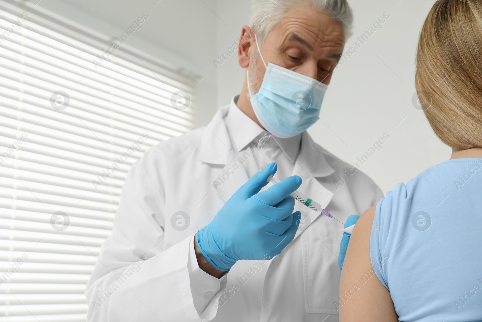 Photo of Doctor giving hepatitis vaccine to patient in clinic. Space for text