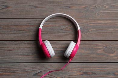 Stylish headphones on wooden background, top view