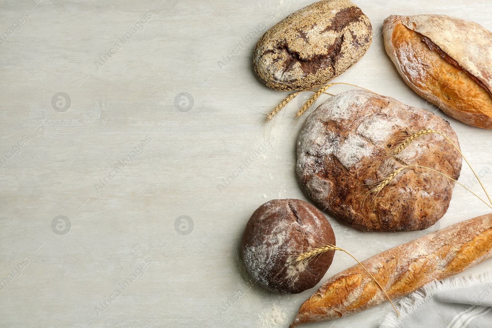 Photo of Different kinds of fresh bread on white wooden table, flat lay. Space for text