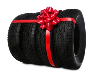 Photo of Winter tires with red ribbon on white background