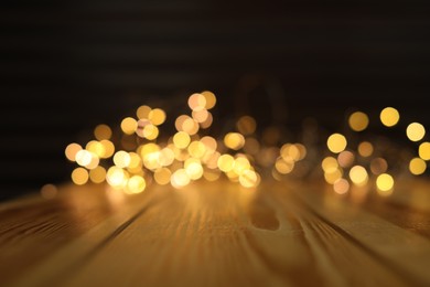 Photo of Empty wooden surface and blurred lights on background. Bokeh effect