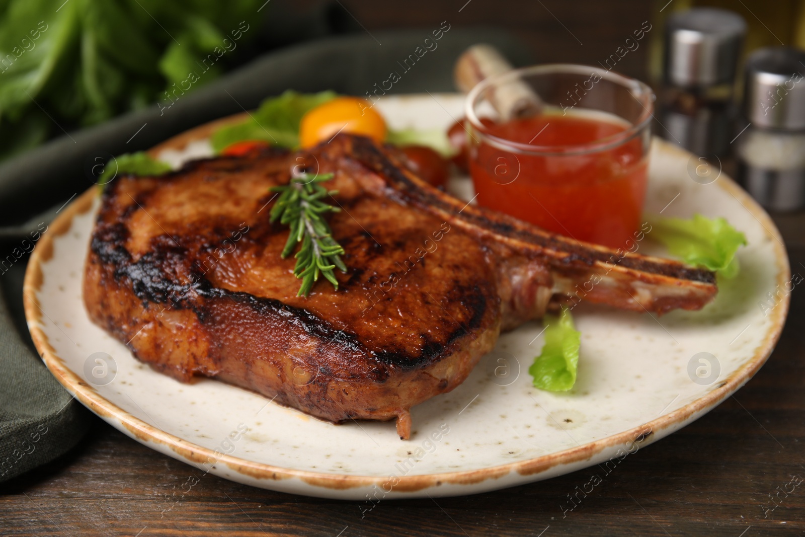 Photo of Tasty grilled meat, rosemary and marinade on wooden table, closeup