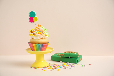 Photo of Birthday cupcake and gift boxes on beige background