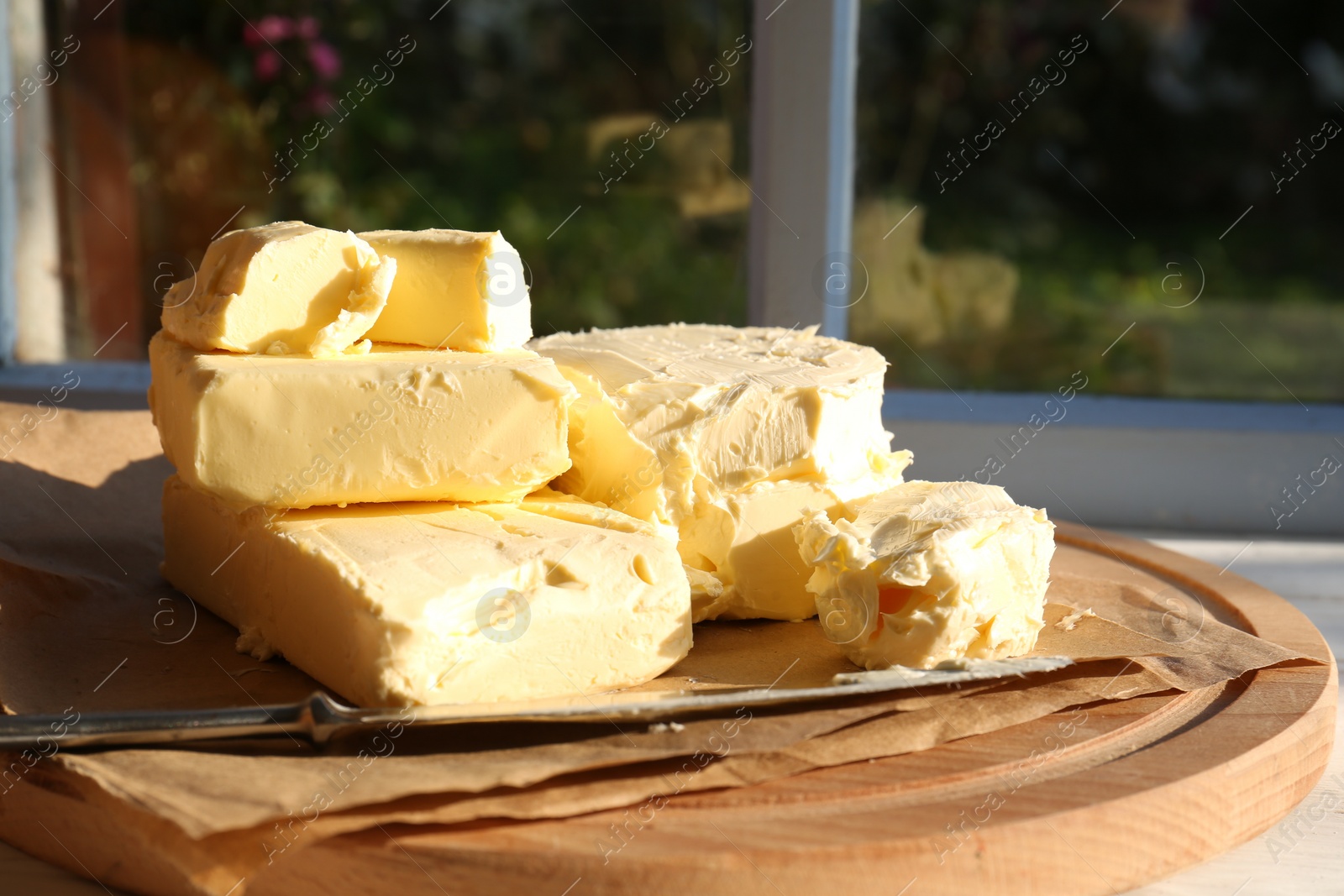Photo of Tray with tasty homemade butter and knife on white wooden windowsill