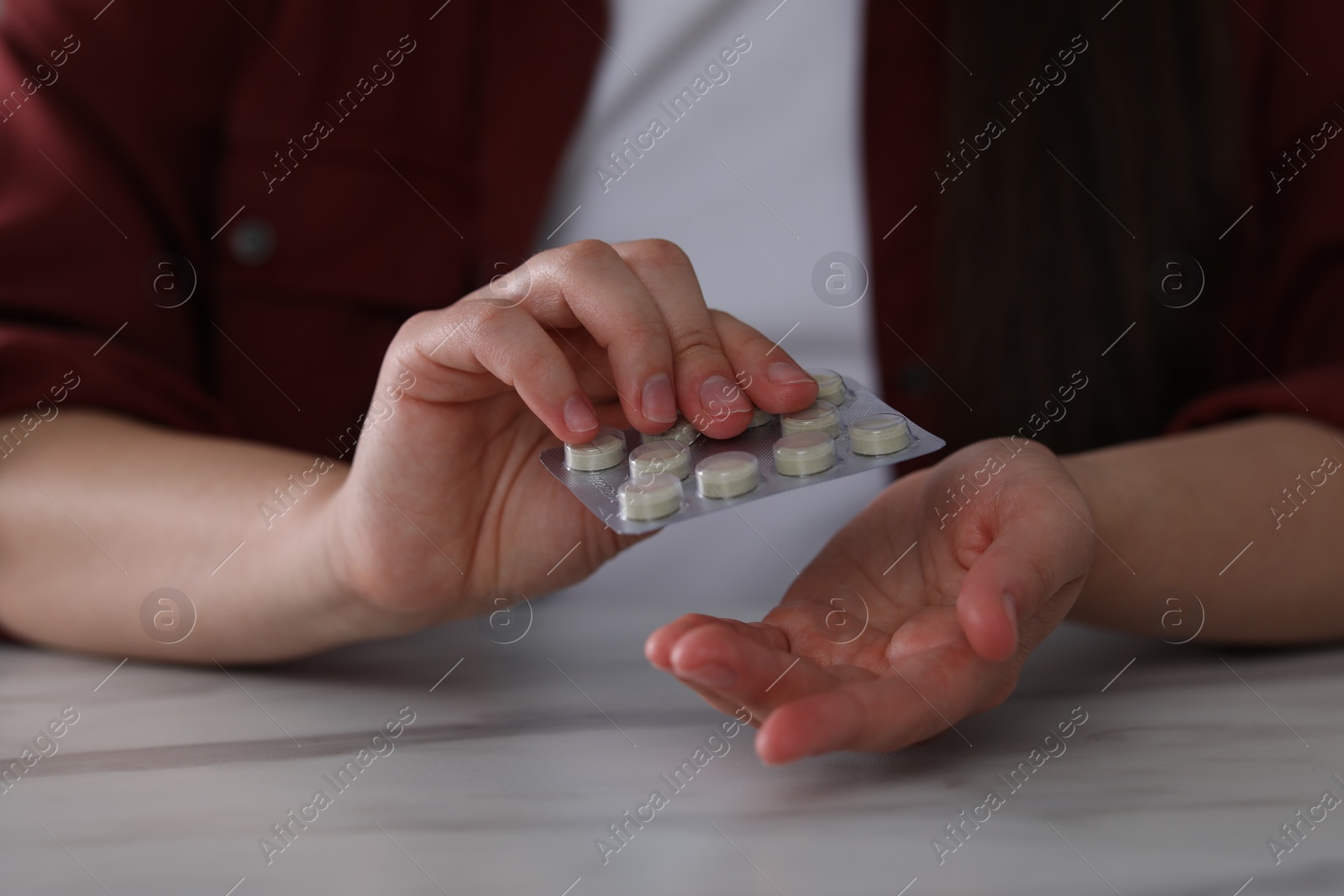 Photo of Woman taking antidepressant pill out from blister at white marble table, closeup