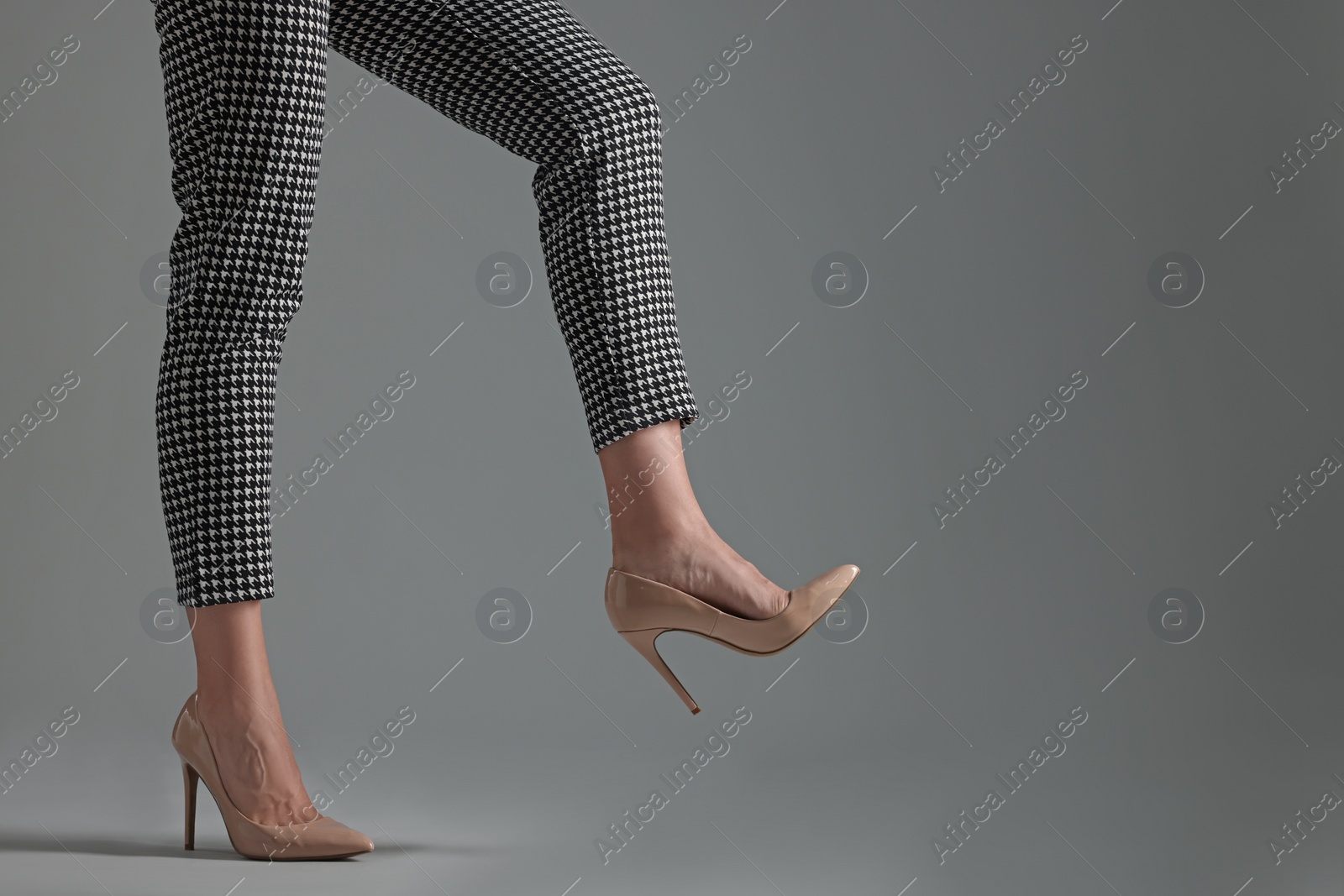 Photo of Businesswoman in beige shoes on grey background, closeup. Space for text