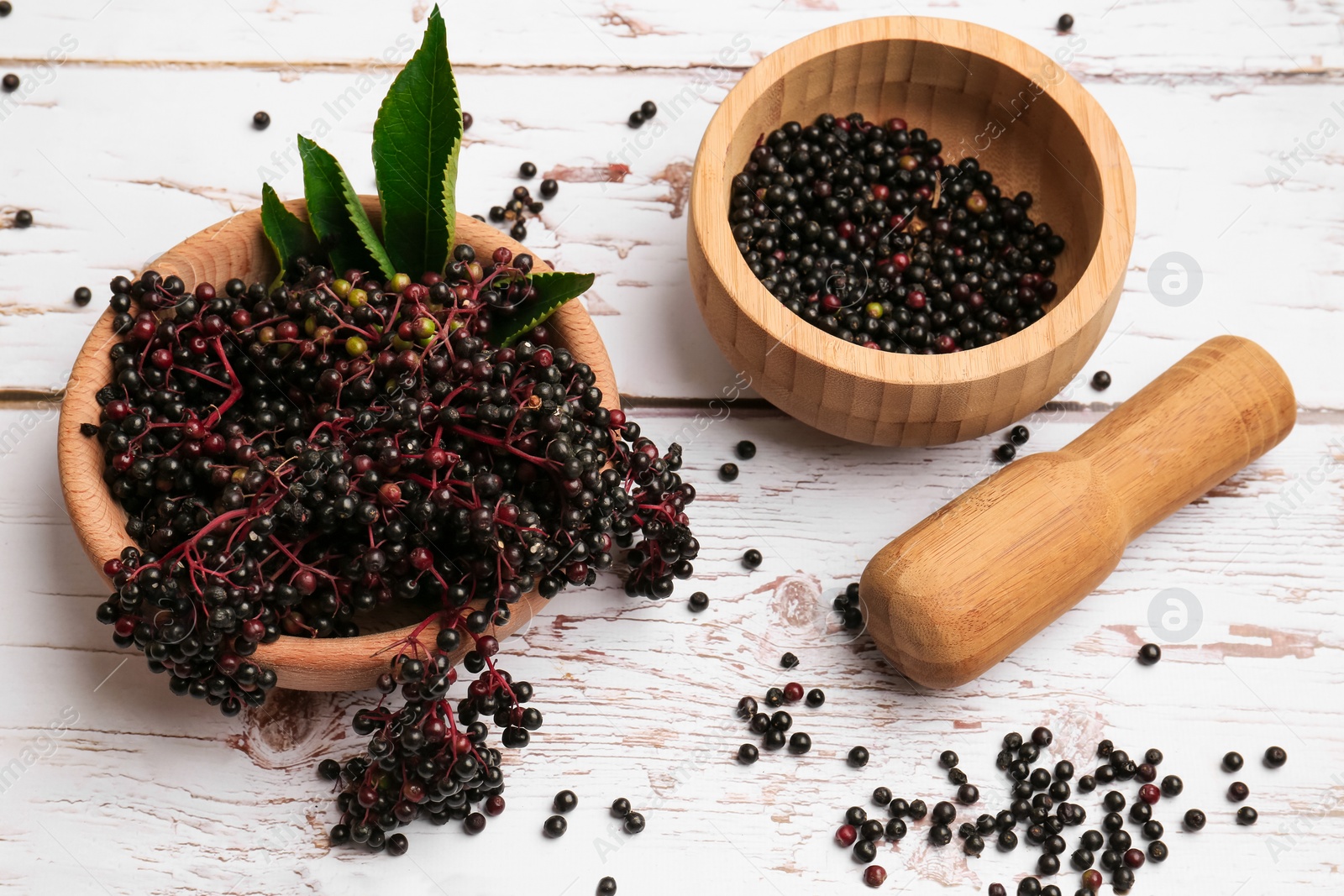 Photo of Tasty elderberries (Sambucus) on white wooden table, above view