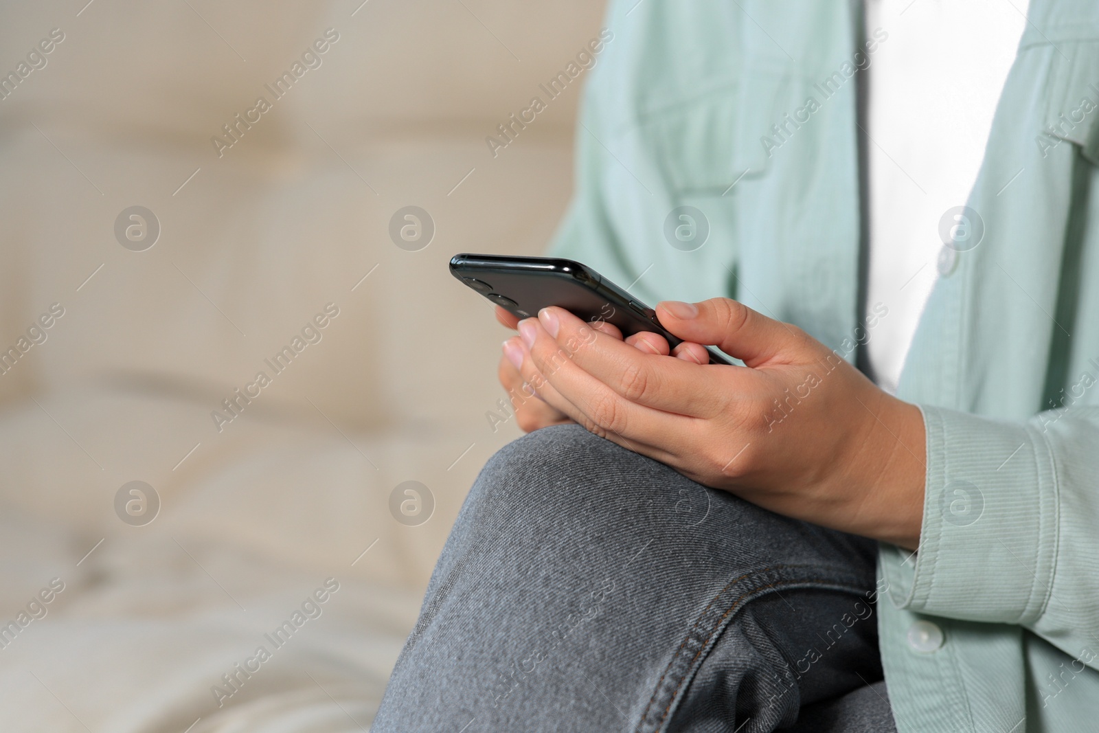 Photo of Woman using smartphone on sofa at home, closeup. Space for text