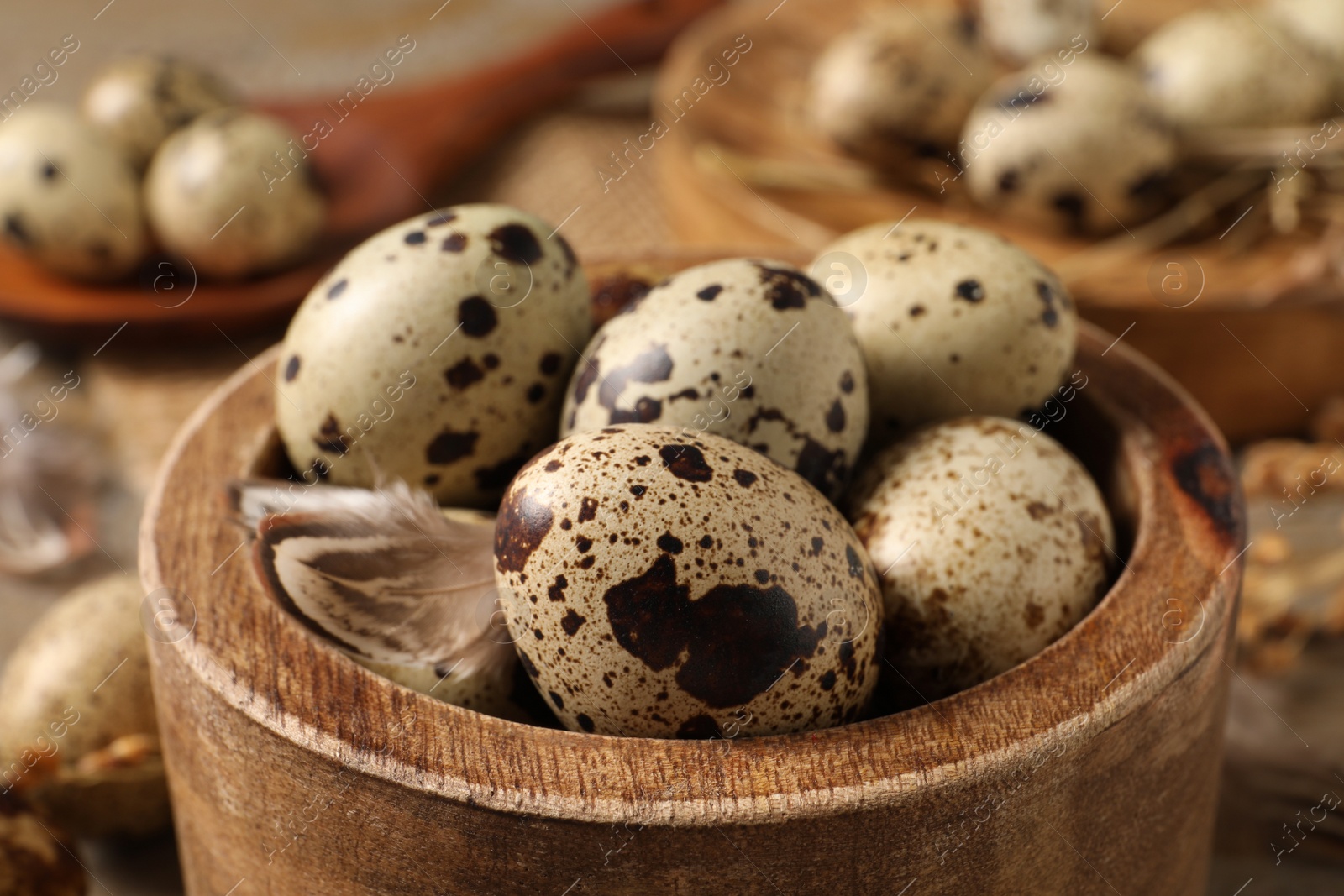 Photo of Wooden bowl with quail eggs on table, closeup