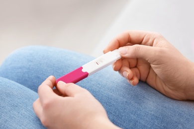 Photo of Young woman with pregnancy test indoors, closeup. Gynecology and childbirth