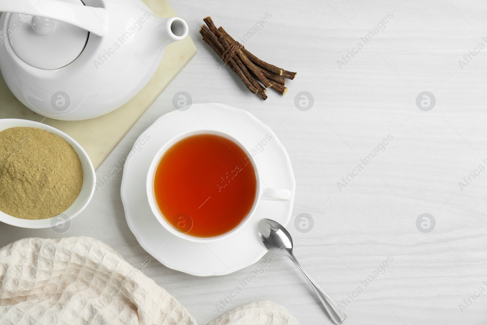 Photo of Aromatic licorice tea in cup served on white wooden table, flat lay. Space for text