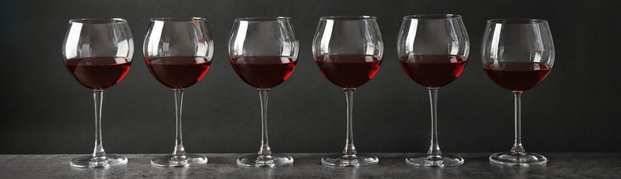 Image of Glasses with tasty red wine on grey table. Banner design