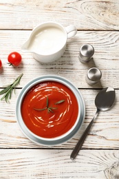 Bowl with fresh homemade tomato soup on wooden table, top view