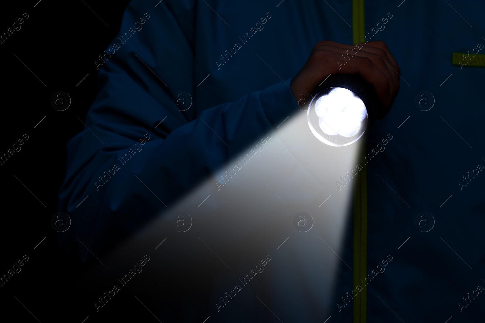 Image of Man with bright flashlight in darkness, closeup