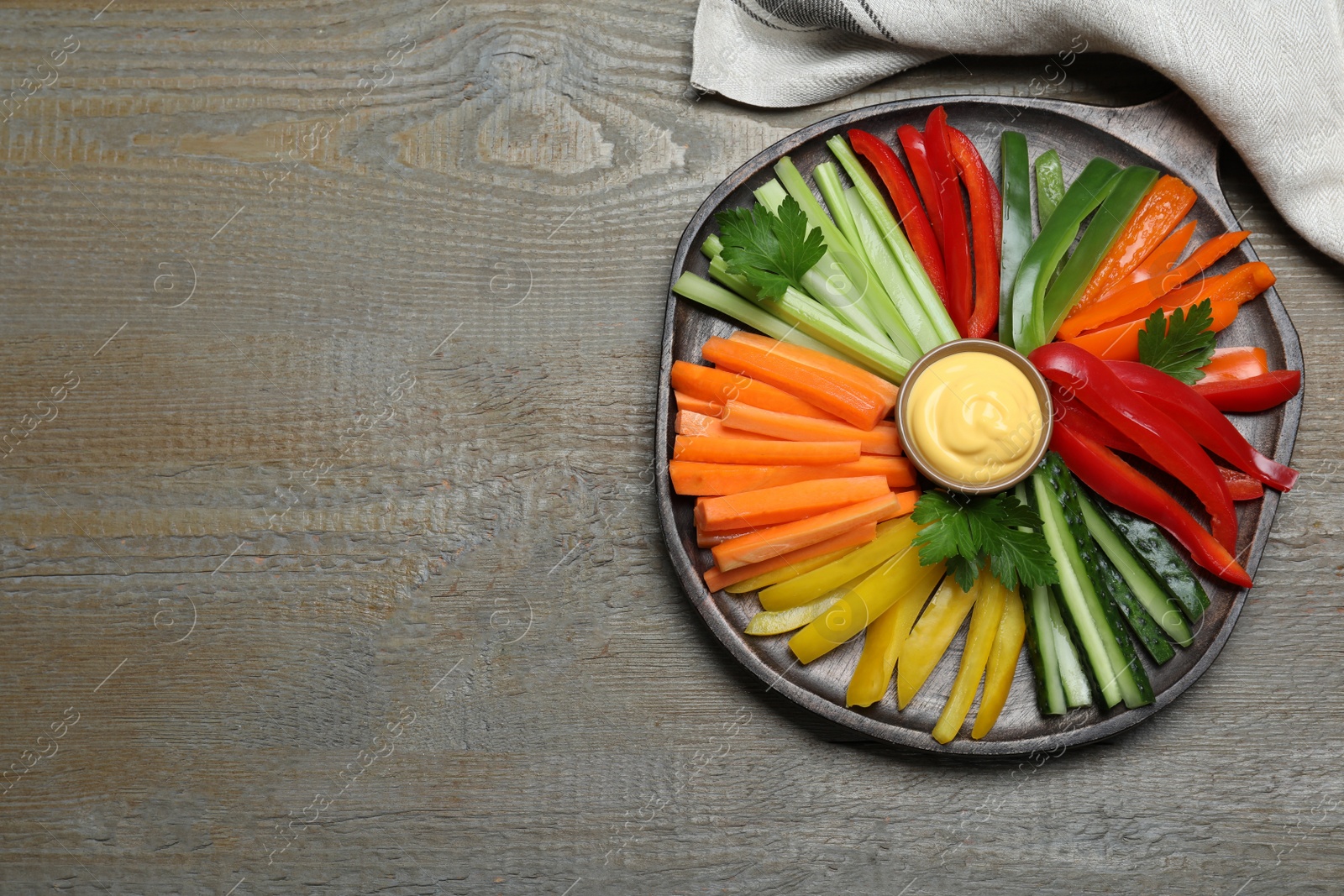 Photo of Different vegetables cut in sticks and dip sauce on wooden table, top view. Space for text