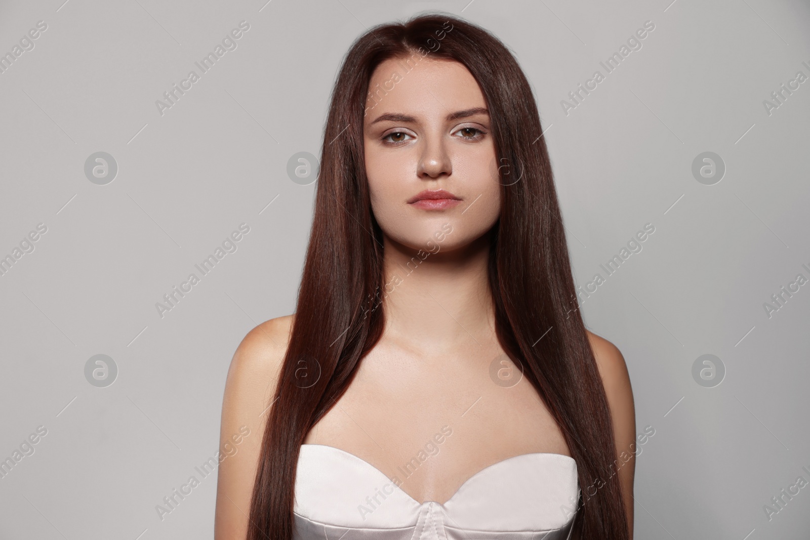 Photo of Portrait of beautiful young woman with healthy strong hair on light gray background