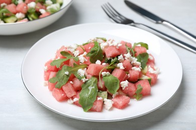 Photo of Delicious salad with watermelon, cucumber, arugula and feta cheese on white wooden table