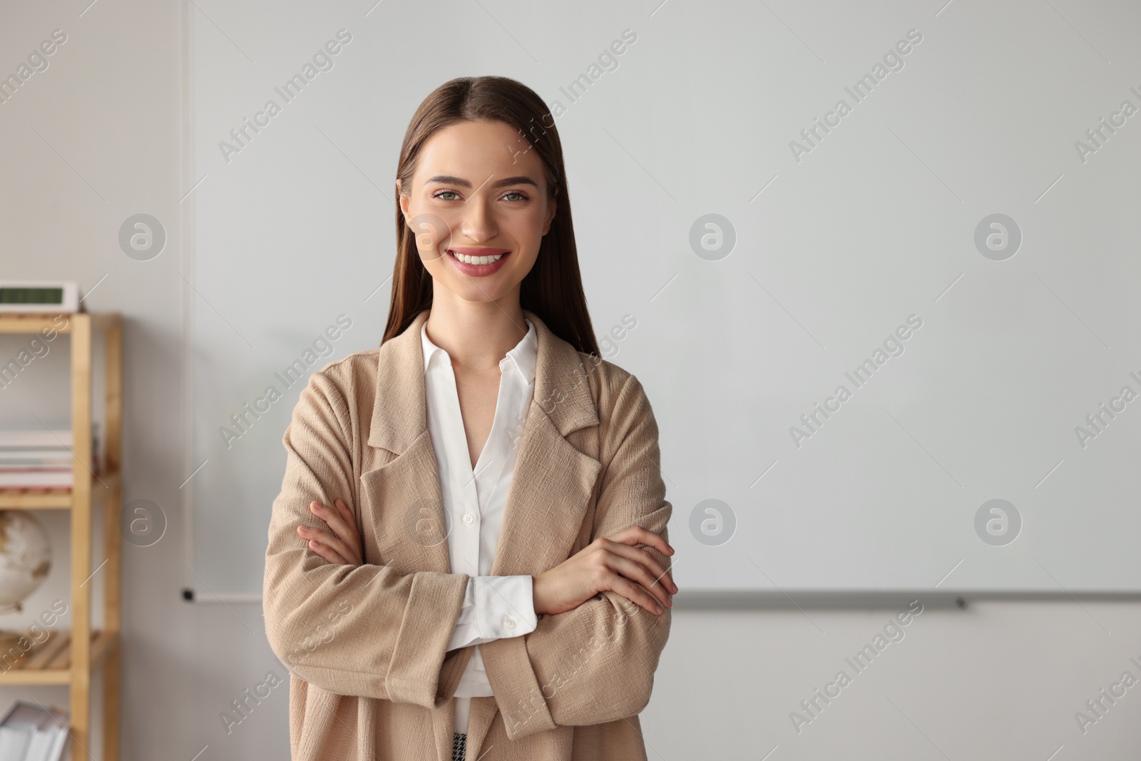 Photo of Happy young teacher at whiteboard in classroom. Space for text