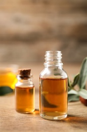 Photo of Glass bottles with jojoba oil on wooden table