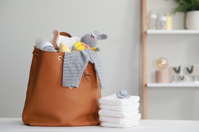 Photo of Mother's bag with baby's stuff on white wooden table indoors. Space for text