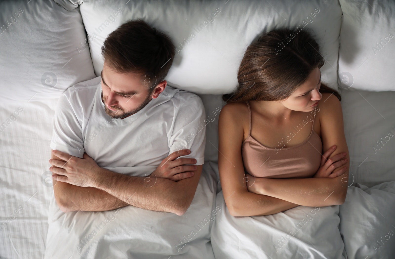 Photo of Unhappy couple with relationship problems after quarrel in bed, above view