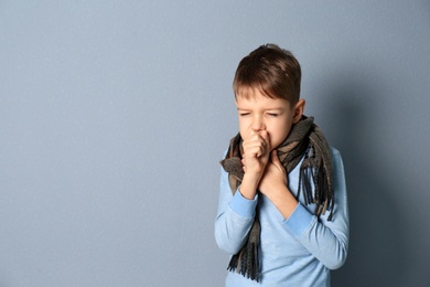 Photo of Little boy coughing on grey background