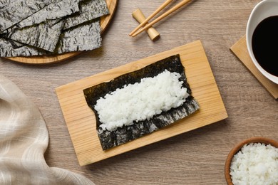 Photo of Dry nori sheet with rice on wooden table, flat lay