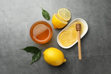 Sweet honey and fresh lemons on grey table, flat lay