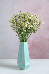 Vase with beautiful chamomile flowers on white wooden table