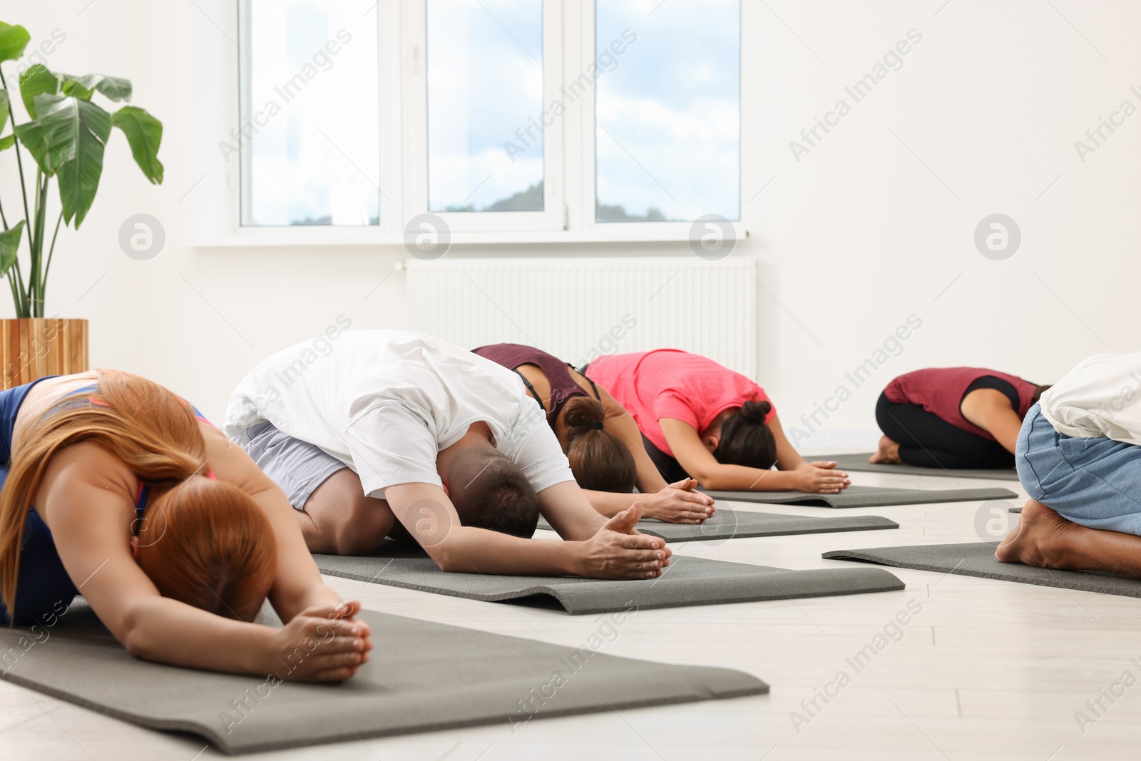 Photo of Group of people practicing yoga on mats indoors