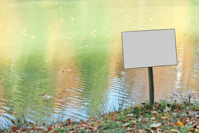 Empty sign board near pond. Space for text