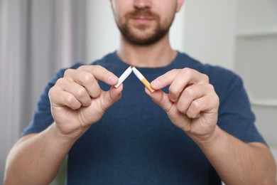 Photo of Stop smoking concept. Man holding pieces of broken cigarette indoors, closeup