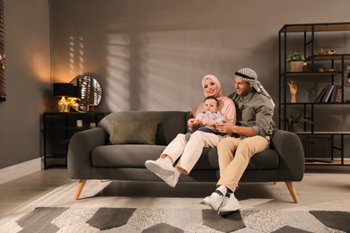 Happy Muslim family with little son in living room