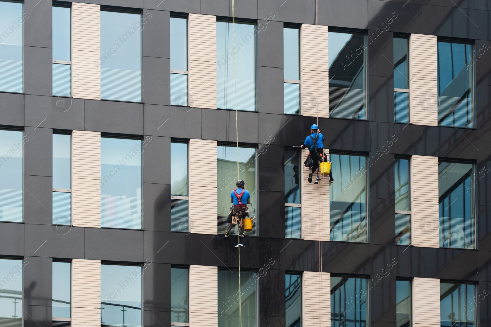 Photo of Men washing windows on modern building outdoors