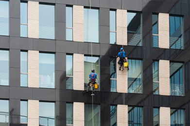 Men washing windows on modern building outdoors