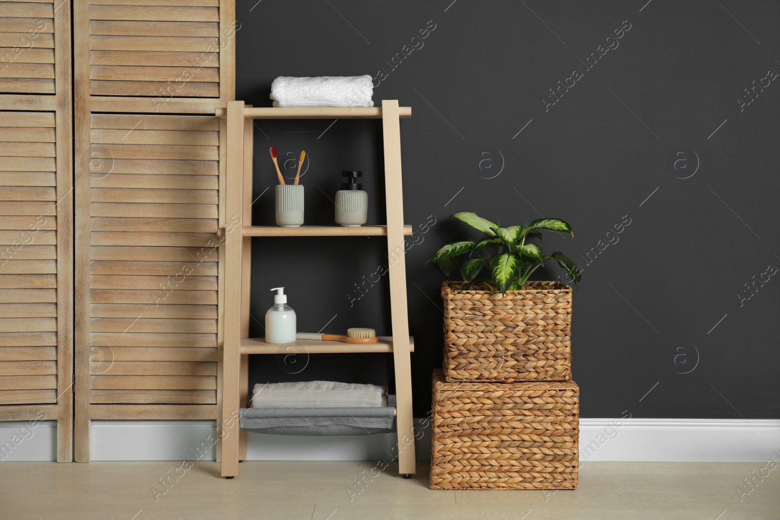 Photo of Wooden shelving unit with toiletries near black wall indoors. Bathroom interior element