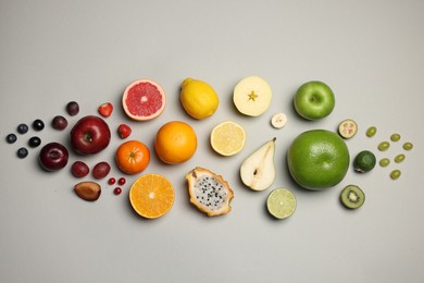 Different ripe fruits and berries on light gray background, flat lay