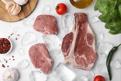 Flat lay composition with cut fresh beef meat on white tiled table