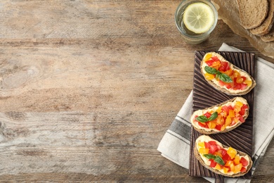 Photo of Tasty fresh tomato bruschettas on wooden table, flat lay. Space for text