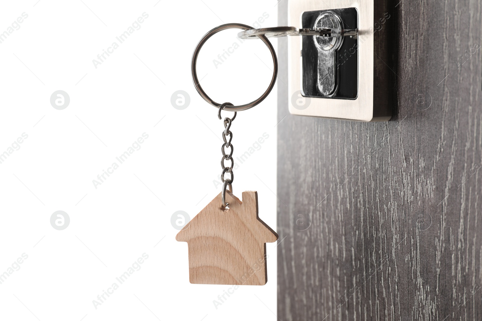 Photo of Mortgage and real estate. Open door with key and house shaped keychain on white background, space for text