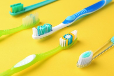 Photo of Many different toothbrushes on yellow background, closeup