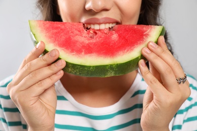 Photo of Beautiful young woman eating watermelon on grey background, closeup