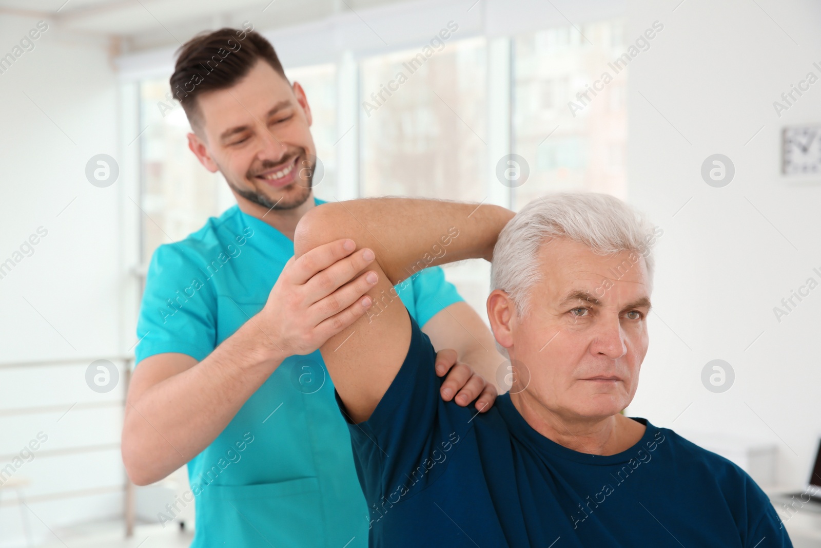 Photo of Young physiotherapist working with senior patient in clinic