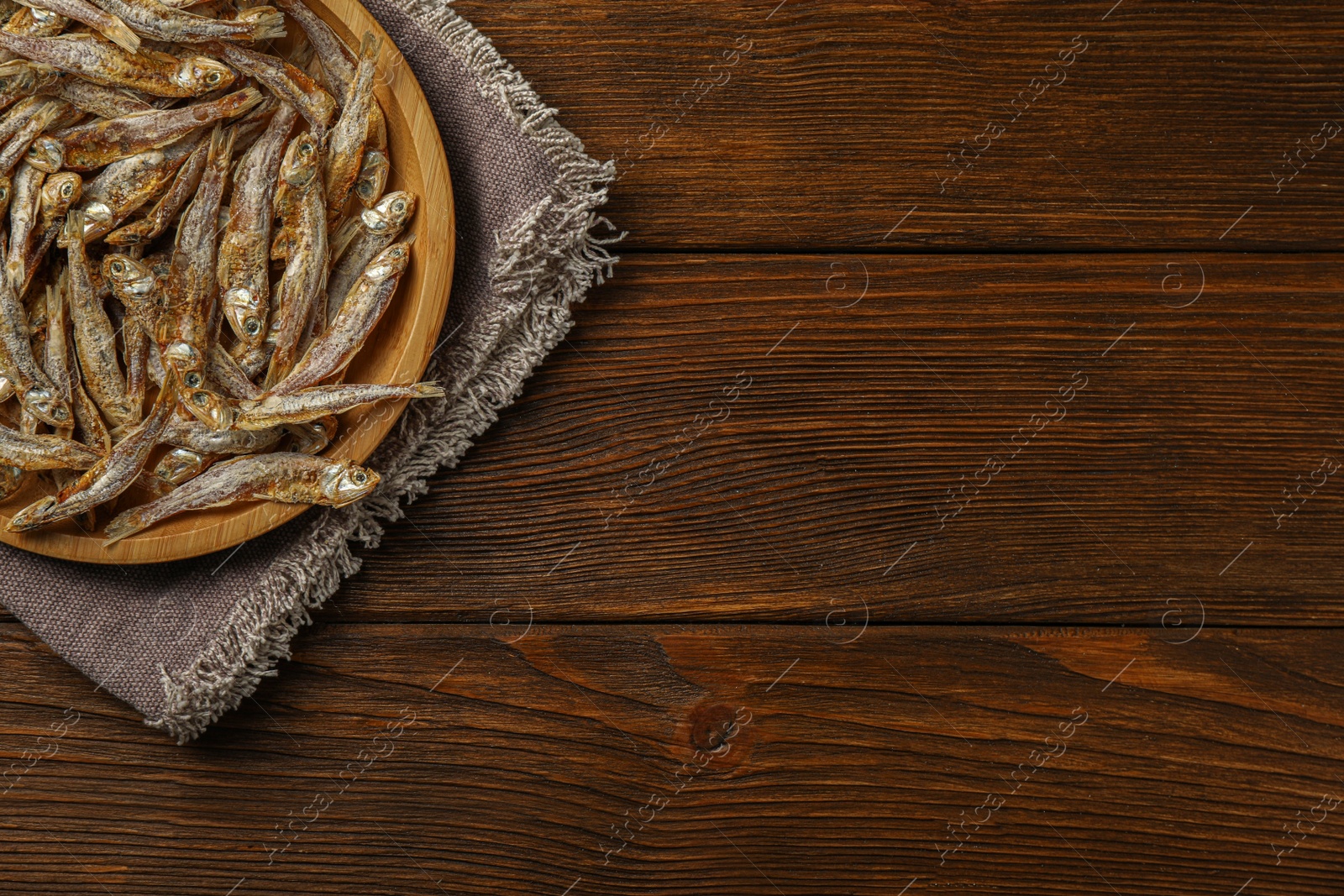 Photo of Tasty dried anchovies on wooden table, top view. Space for text