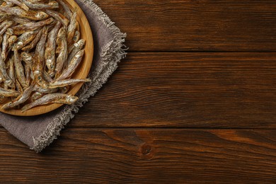 Tasty dried anchovies on wooden table, top view. Space for text