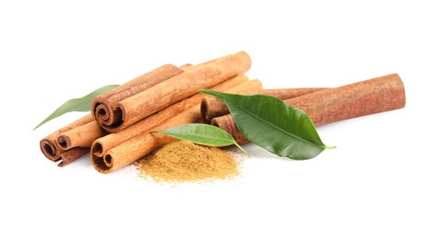 Photo of Dry aromatic cinnamon sticks, powder and green leaves isolated on white