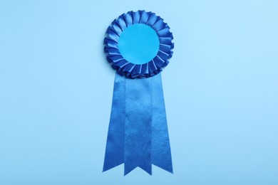 Photo of Blue award ribbon on turquoise background, top view
