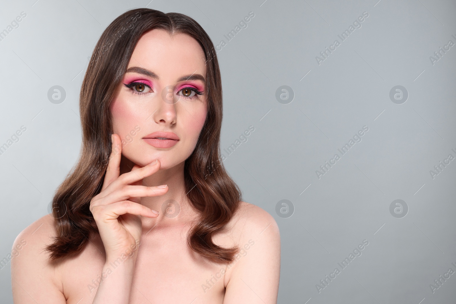 Photo of Portrait of beautiful young woman with makeup and gorgeous hair styling on light grey background. Space for text